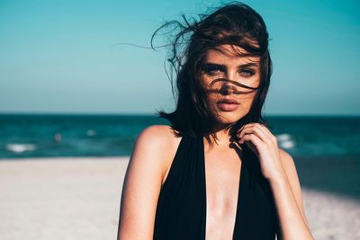 Portrait of young woman standing at beach