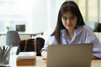 Portrait of mid adult woman using laptop on table