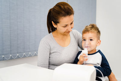 Smiling mother sitting with son wearing oxygen mask