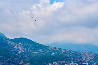 People flying over mountain against sky