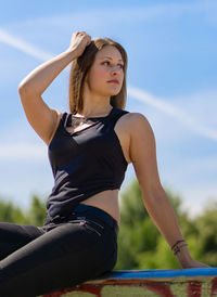 Beautiful young woman looking away against sky