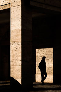 Silhouette man walking against building
