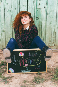 Portrait of young woman sitting on wood