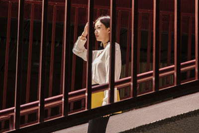 Woman looking away while standing against railing