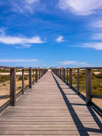 Pier on beach against blue sky