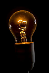 Close-up of illuminated light bulb against black background