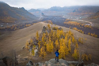 High angle view of hiker standing on rock against landscape during autumn