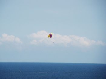 Low angle view of parachute flying above sea against sky