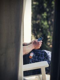 Midsection of man using phone while sitting on chair