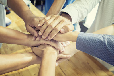 High angle view of business people stacking hands over desk in office