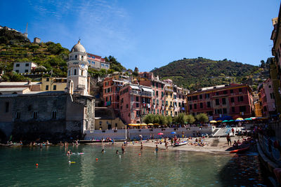 People swimming in pool against clear blue sky