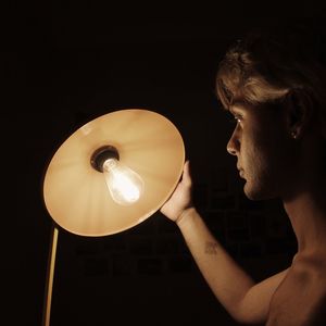 Close-up of woman holding illuminated light bulb