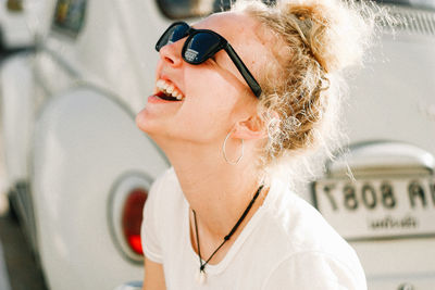 Close-up of woman wearing sunglasses while smiling against car