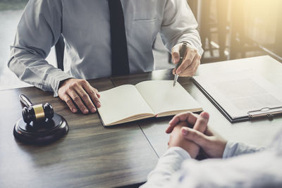 Midsection of man reading book on table