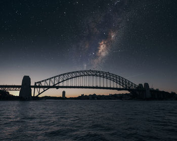 Scenic view of bridge over river against sky in city at night