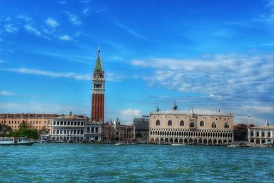 View of church at waterfront against cloudy sky