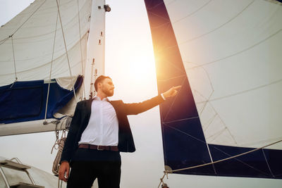 Man standing on sailboat against sky