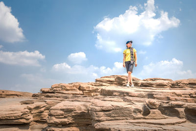 Man standing on rock against sky