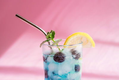 Close-up of a colorful summer blue curacao cocktail on a pink background with trendy shadows. 