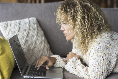 Side view of woman using laptop on sofa