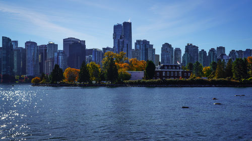 Buildings by river against sky in city