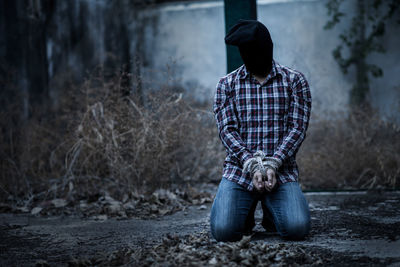 Rear view of man sitting on field in forest