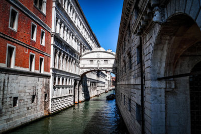 Arch bridge over canal amidst buildings in city