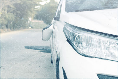 Close-up of snow covered car on road