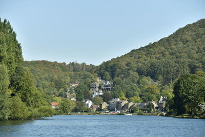 Scenic view of river amidst trees and buildings against sky