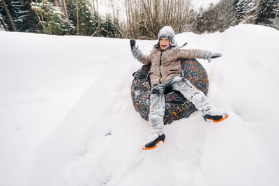 A happy boy is sitting in a tubing in the snow and riding down a slide