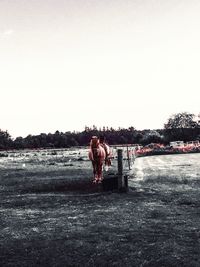 Man standing on riverbank against clear sky