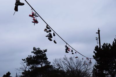Low angle view of shoes hanging from cable against sky
