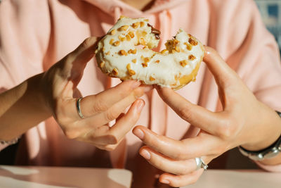 Midsection of woman eating donut at table