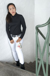 Portrait of young woman standing against white wall