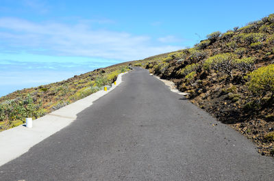 Empty road amidst land against sky