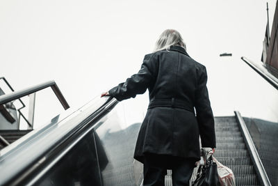 Rear view of woman standing on railing against clear sky
