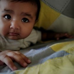 Close-up portrait of cute baby lying on bed