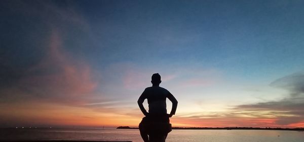 Rear view of silhouette man sitting on beach