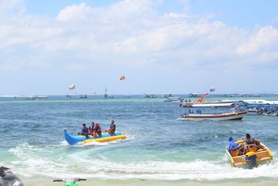 People on boat in sea against sky