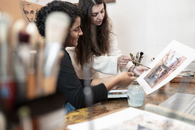 Young female painters discussing over painting at studio