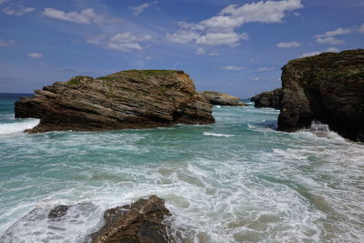 Scenic view of rocks in sea against sky