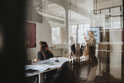 Businesswoman discussing over presentation with male and female colleagues in board room at office