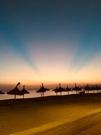 Silhouette people on beach against sky during sunset