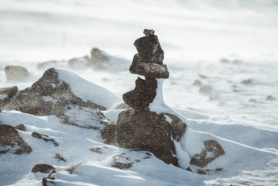 Stacked rocks on snow covered field during winter