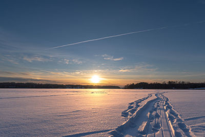 Scenic view of snow covered field against sky during sunset