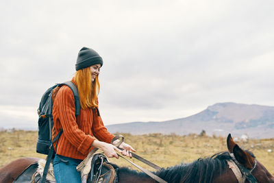 Man riding horse cart on mountain against sky