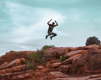 Man jumping on rock against teal sky on grand canyon