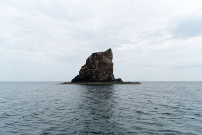 Rock formation in sea against sky