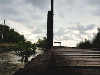 Empty benches on footpath by pier against sky