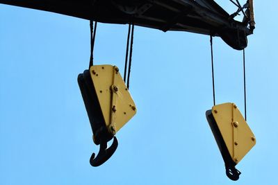 Low angle view of crane against clear blue sky